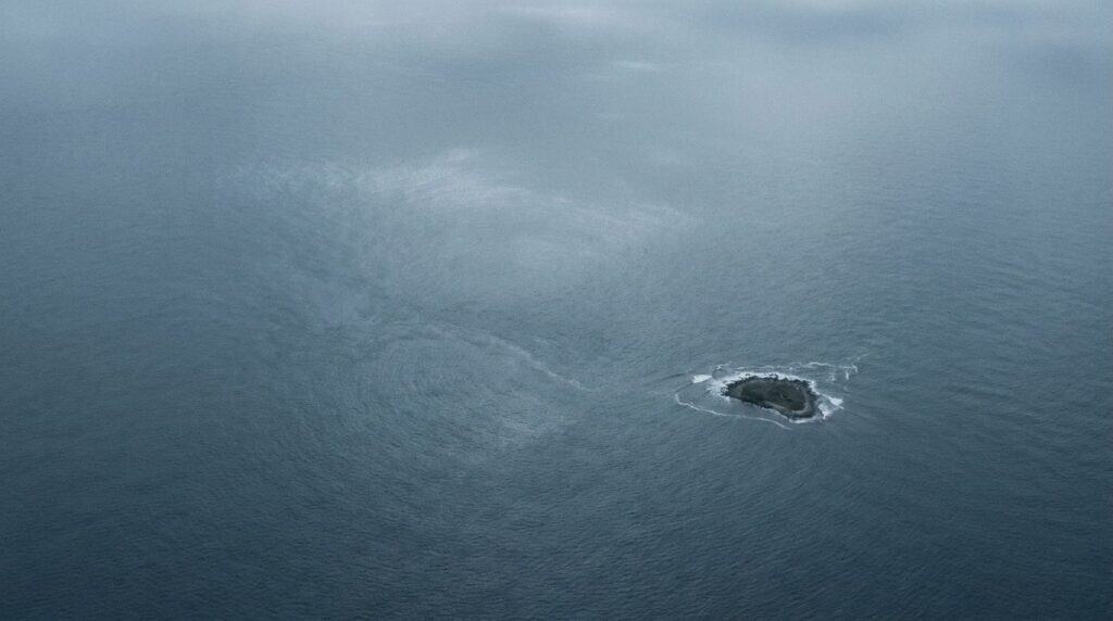 Vista aérea de uma pequena ilha remota em mar aberto, ilustrando as jurisdições offshore onde ficam as entidades que assinam contrato com o cliente brasileiro
